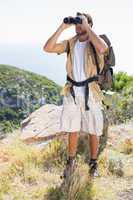 Handsome hiker looking through binoculars