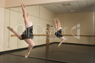 Beautiful ballerina dancing in front of mirror