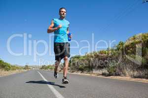 Athletic man jogging on open road holding bottle