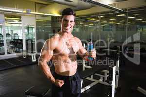 Muscular man holding energy drink in gym