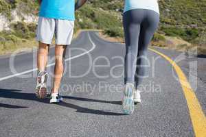 Fit couple running together down a road