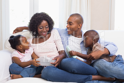 Happy family on the couch giving mother presents