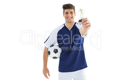 Football player in blue jersey holding winners trophy