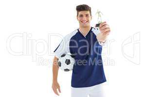 Football player in blue jersey holding winners trophy