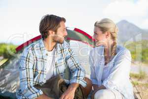 Attractive hiking couple smiling at each other outside their ten