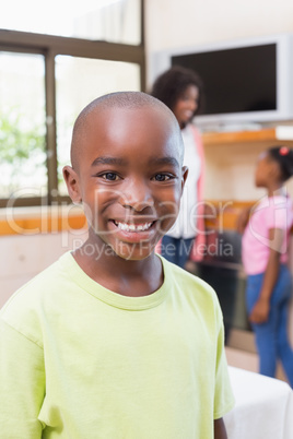 Cute little boy smiling at camera with family in background