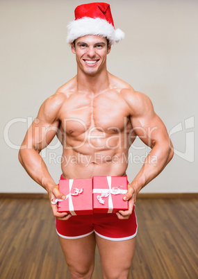 Shirtless macho man in santa hat holding gifts