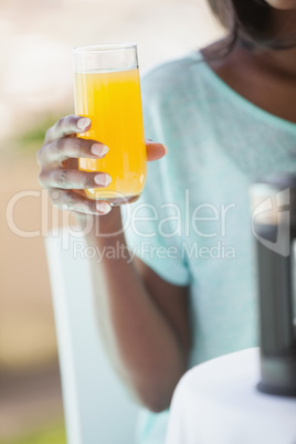 Smiling woman having orange juice outside