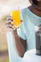Smiling woman having orange juice outside