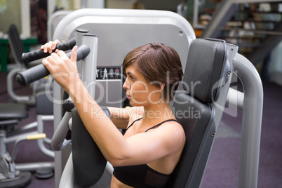 Happy brunette using weights machine for arms