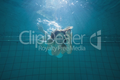 Pretty brunette smiling and offering her hand underwater
