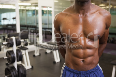 Mid section of a shirtless muscular man in gym