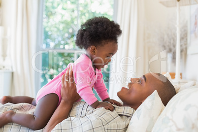 Happy father and baby girl lying on bed together