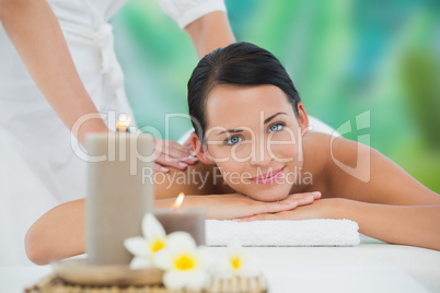 Beautiful brunette enjoying a back massage smiling at camera