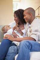 Happy parents spending time with baby on the couch