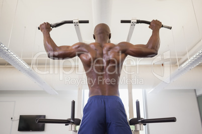 Male body builder doing pull ups at the gym