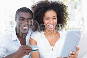 Attractive couple using tablet together on sofa to shop online