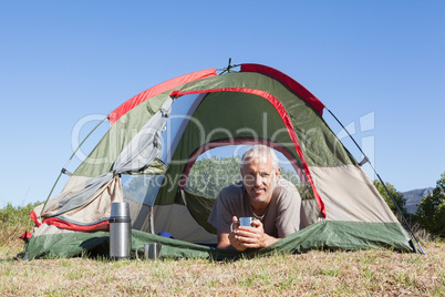 Happy camper smiling at camera lying in his tent