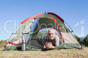 Happy camper smiling at camera lying in his tent