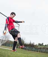 Goalkeeper in red kicking ball away from goal