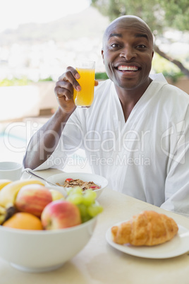 Handsome man in bathrobe having breakfast outside