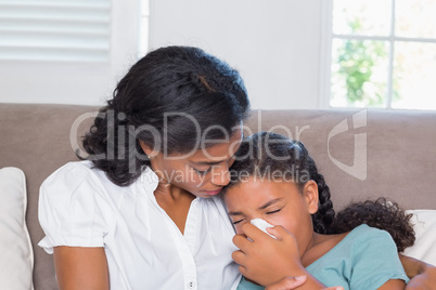 Concerned mother cuddling sick daughter