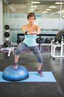 Fit brunette using bosu ball for squats