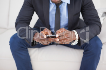 Businessman texting on phone on sofa