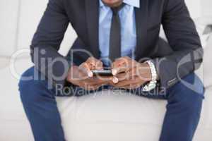 Businessman texting on phone on sofa