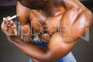 Shirtless muscular man injecting steroids