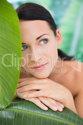 Beautiful nude brunette posing with green leaves