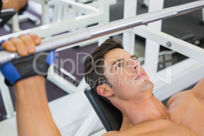 Shirtless muscular man lifting barbell in gym