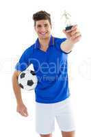 Football player in blue jersey holding winners trophy