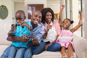 Happy family relaxing on the couch playing video games