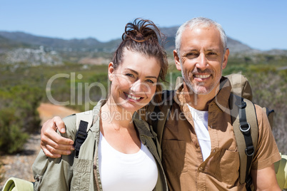Hiking couple smiling at camera on mountain trail