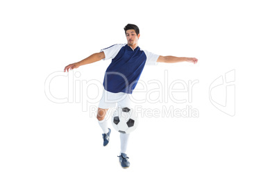 Football player in blue kicking ball