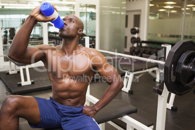 Muscular man drinking energy drink in gym