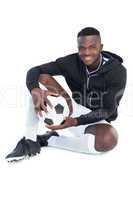 Football player sitting with ball