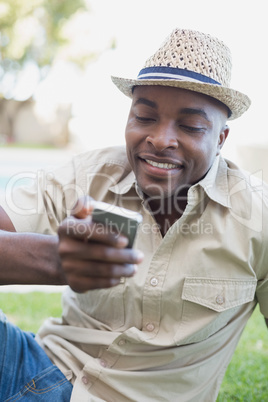 Smiling man relaxing in his garden texting on phone