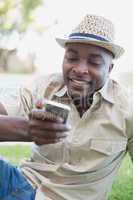 Smiling man relaxing in his garden texting on phone