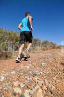 Athletic man jogging up country trail