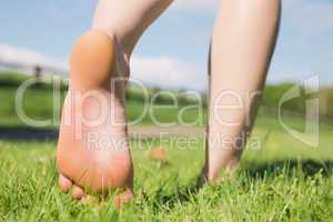 Womans feet walking away on grass