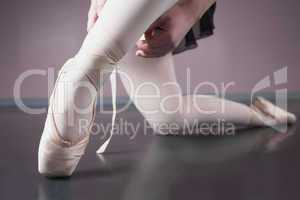 Ballerina tying the ribbon on her ballet slippers