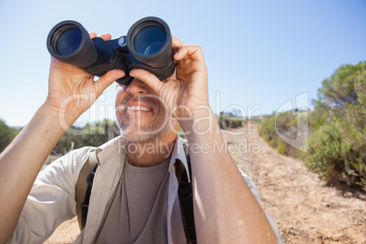 Hiker looking through his binoculars on country trail