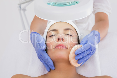 Hands cleaning womans face with cotton swab