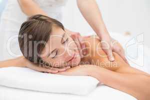 Attractive young woman receiving shoulder massage at spa center