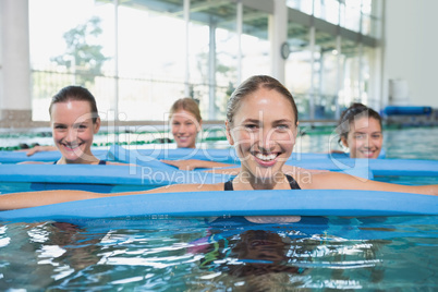 Female fitness class doing aqua aerobics with foam rollers