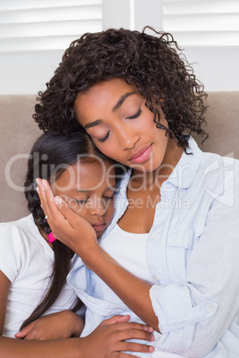 Pretty mother sitting on the couch with her sleeping daughter