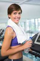 Fit brunette smiling at camera on the treadmill