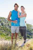 Fit couple standing at summit smiling at camera